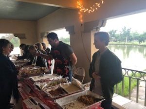 a group of people standing in front of a table full of food