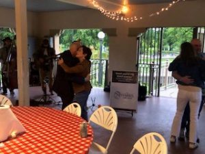 a man and woman hugging in a room with a table and chairs