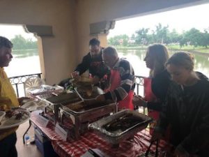 a group of people standing around a table with food