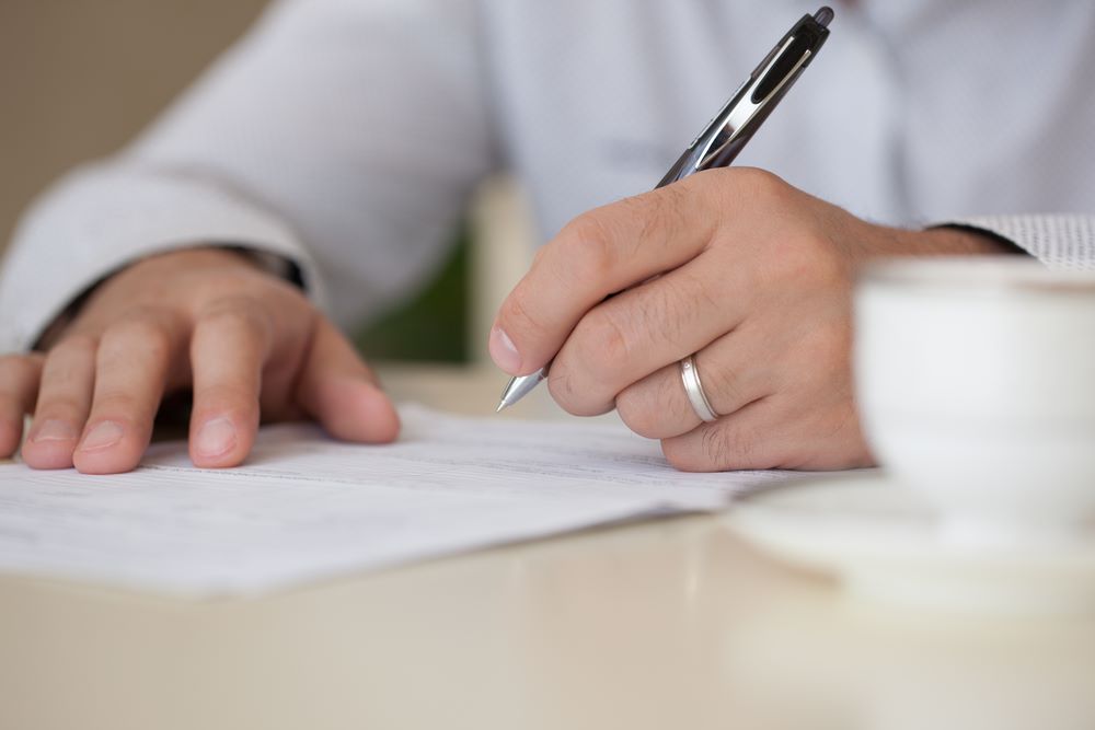 person writing with pen on paper